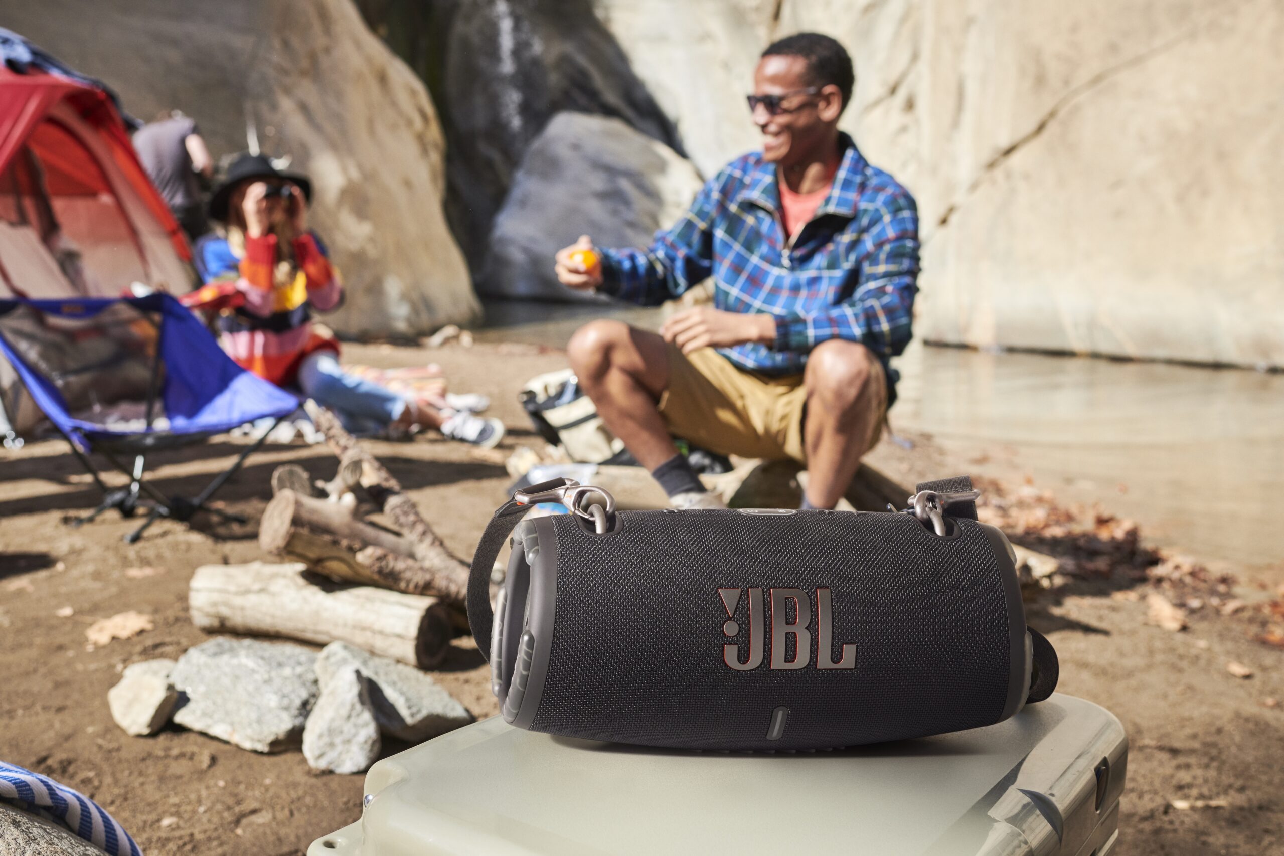 Man and woman at campground, JBL speaker in forgeround